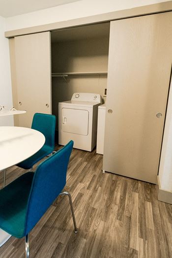 a room with a washing machine and a table and chairs at Aero Apartments, Tacoma